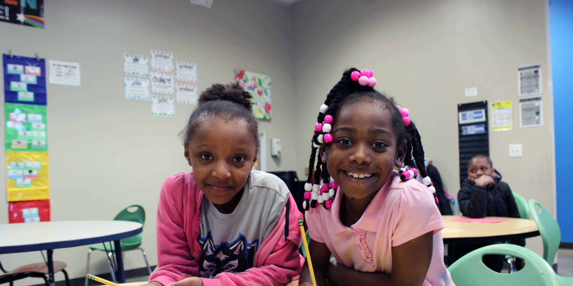Two smiling students seated at a classroom table.
